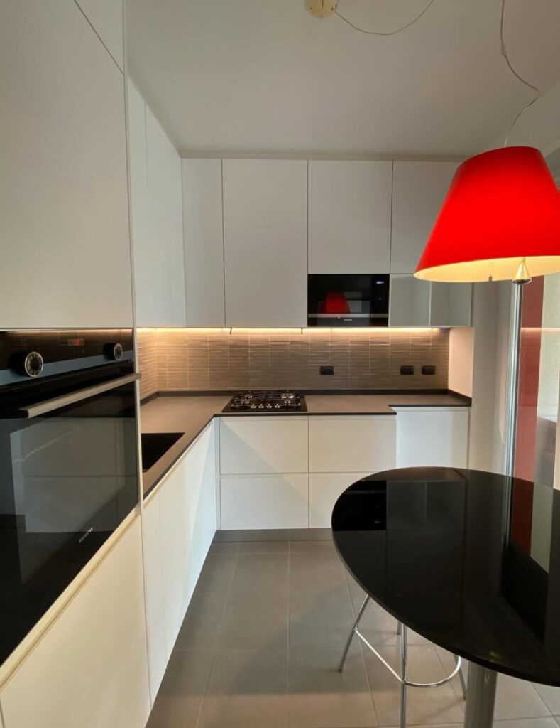 Cucina moderna su misura bianca con layout angolare e illuminazione integrata